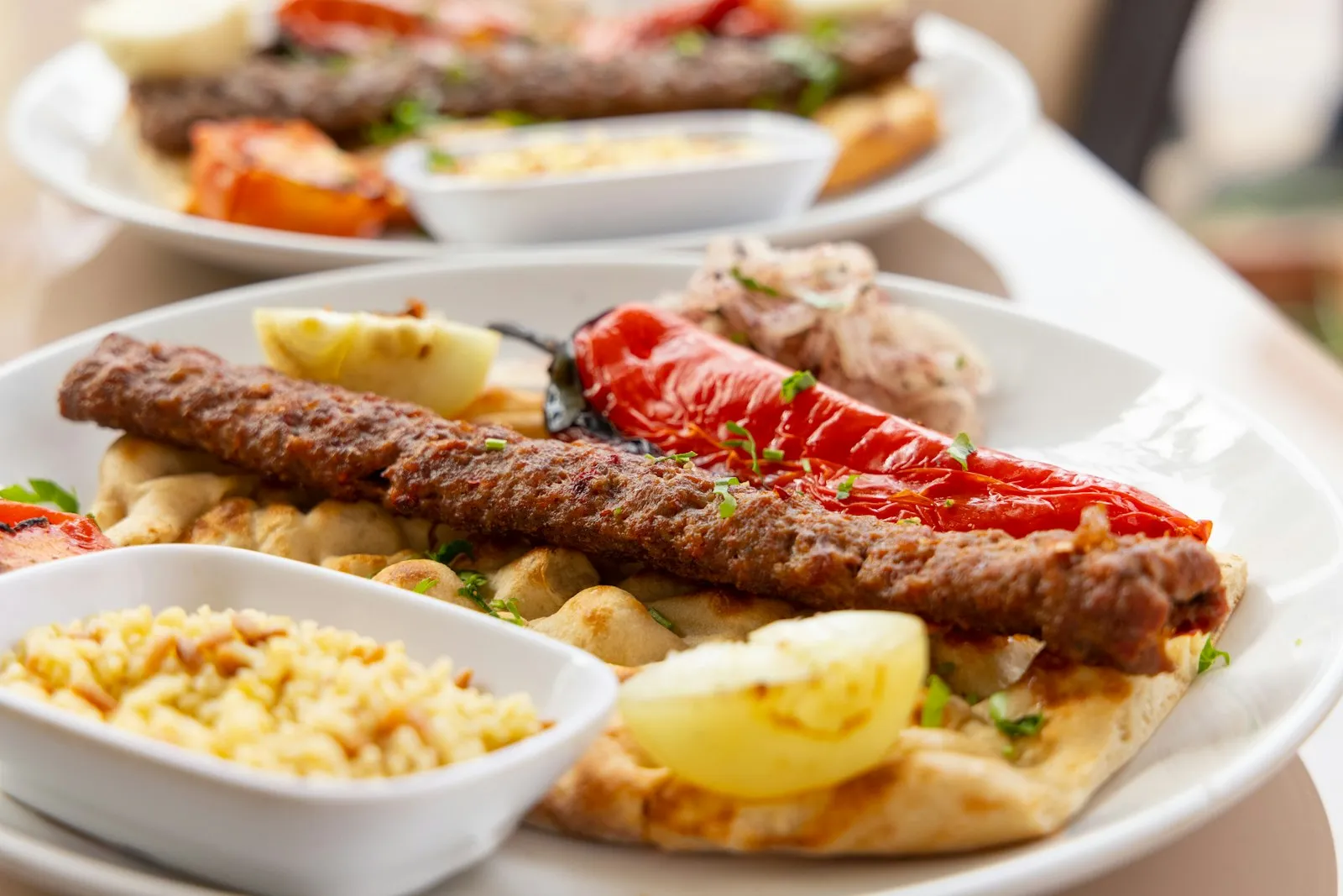 Adanakebab på pitabrød med grillet paprika, sitron og bulgur ved siden av