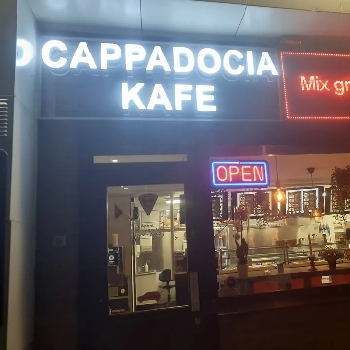 Inngangen til Cappadocia i Sande om kvelden, med det opplyste skiltet «Cappadocia Kafe» og et rødt lysskilt med «Mix grill»